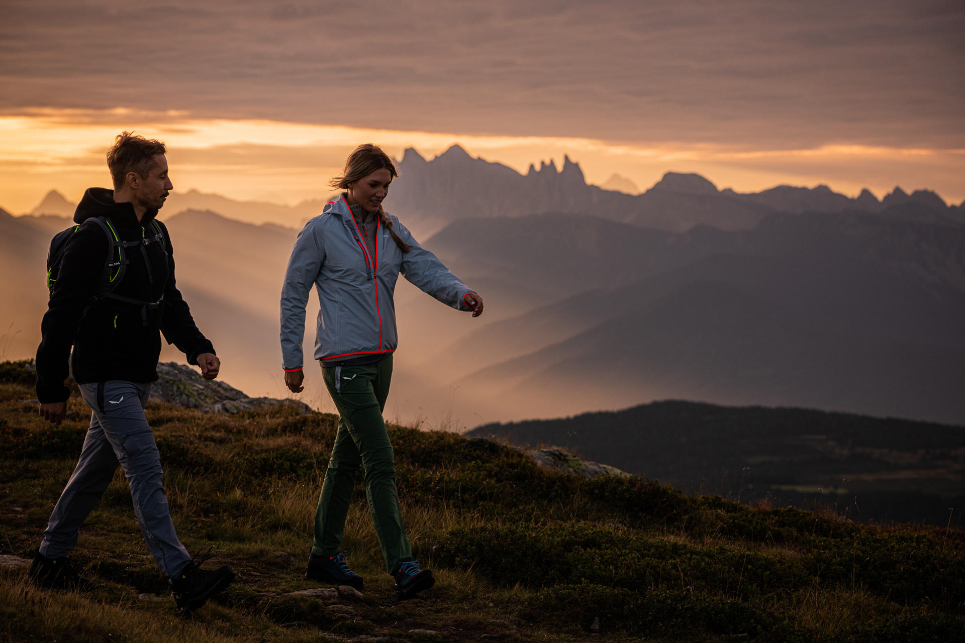 Frau und Mann wandern umgeben von Bergspitzen.